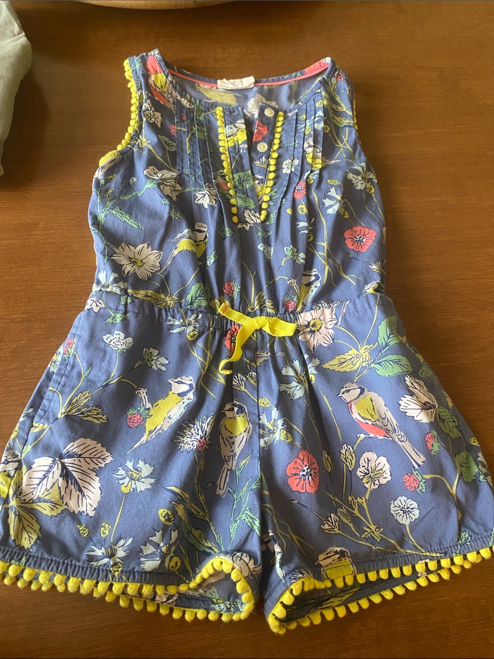 Mini Bowden Girls bird and floral print romper features yellow pom-pom trim.